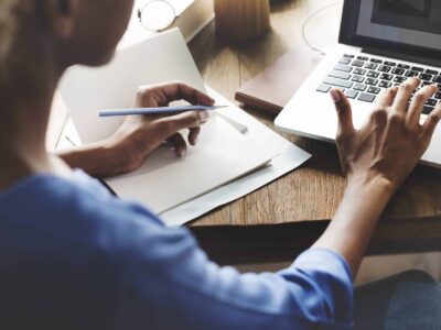 Personne qui prend des notes à côté d'un ordinateur portable