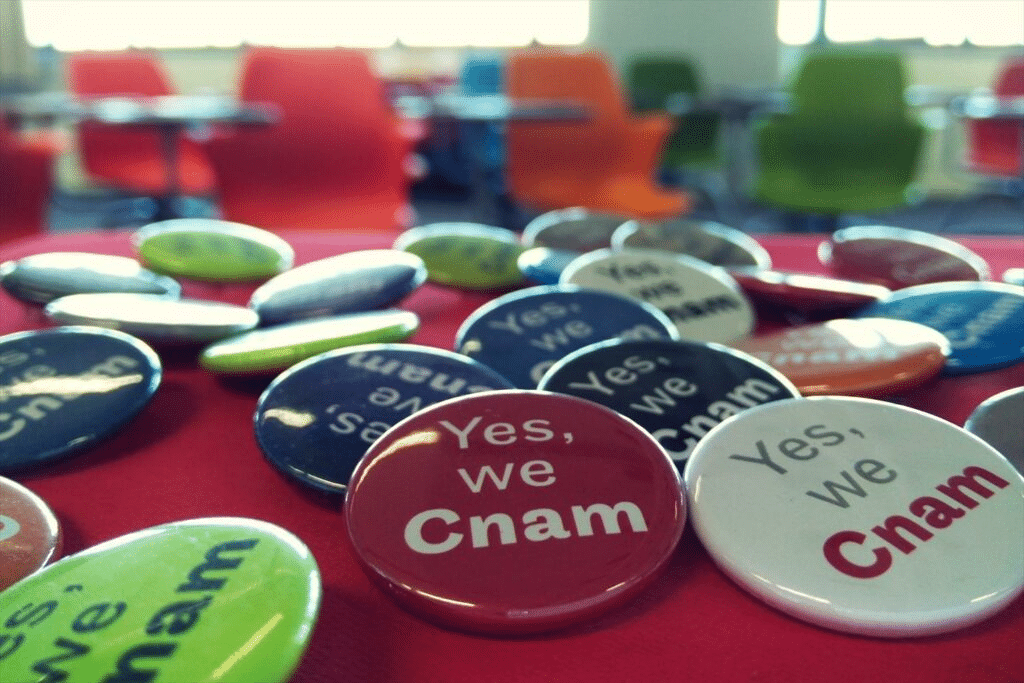 Badges « Yes, we Cnam » posés sur une table
