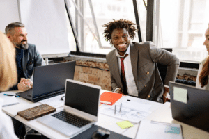 Collègues souriants autour d'une table de travail avec ordinateurs portables
