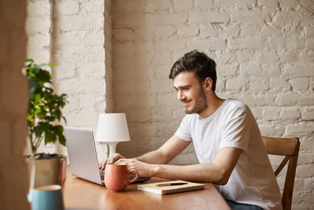 Homme qui suit un cours sur son ordinateur portable, chez lui