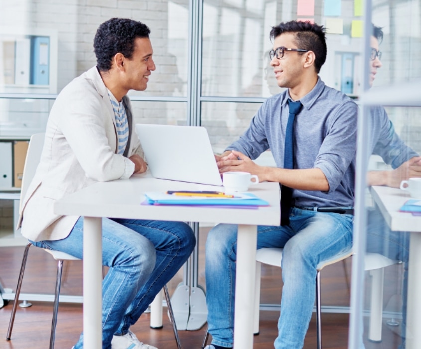 Entretien entre deux hommes autour d'une table, ordinateur ouvert