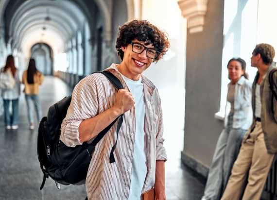 Étudiant souriant avec son sac à dos dans un couloir