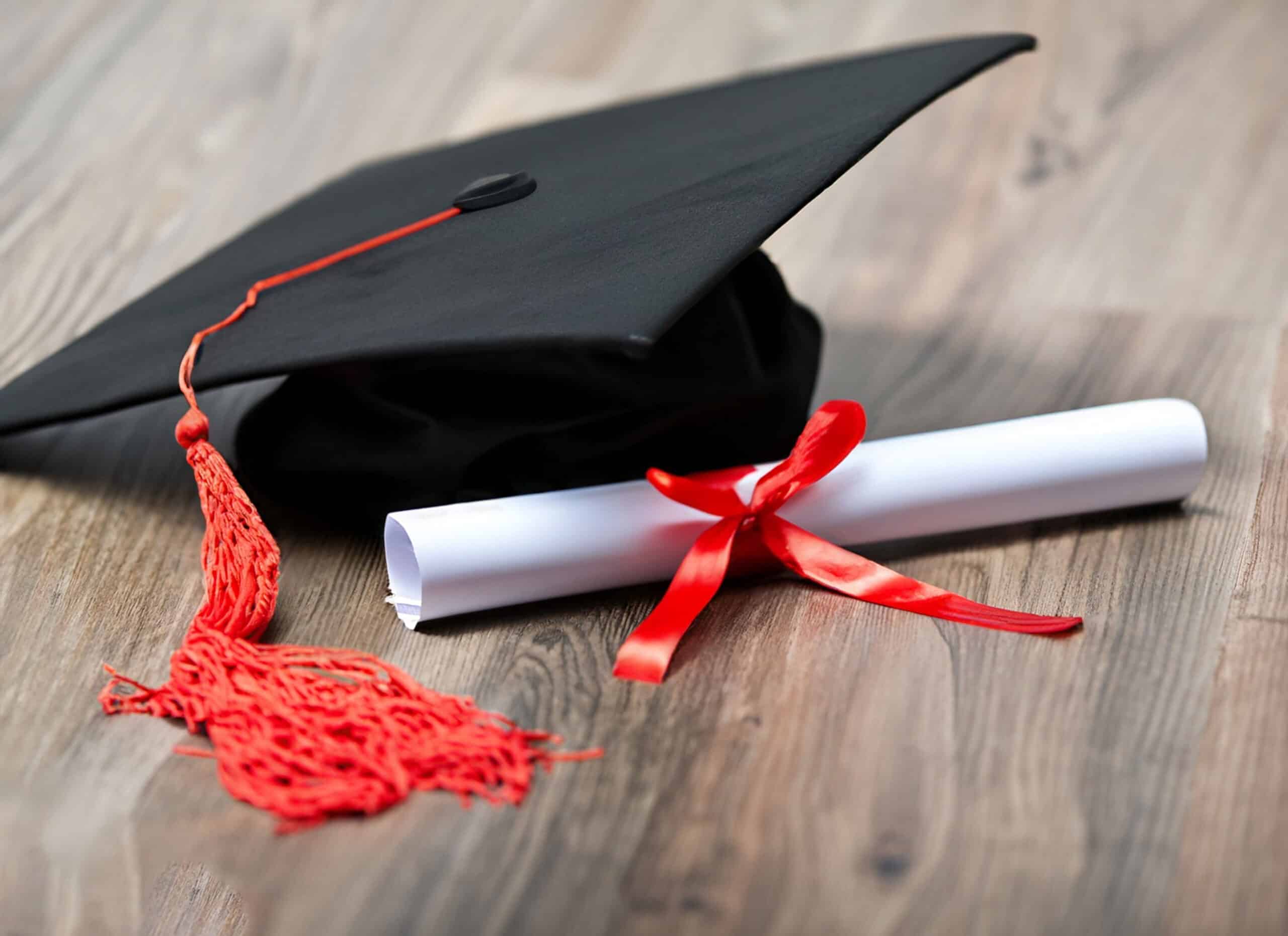 Toque de diplômé et diplôme roulé, noué d'un ruban rouge