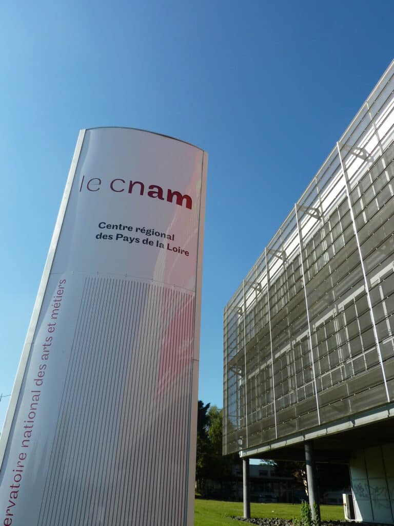 Totem du Cnam devant un bâtiment vitré