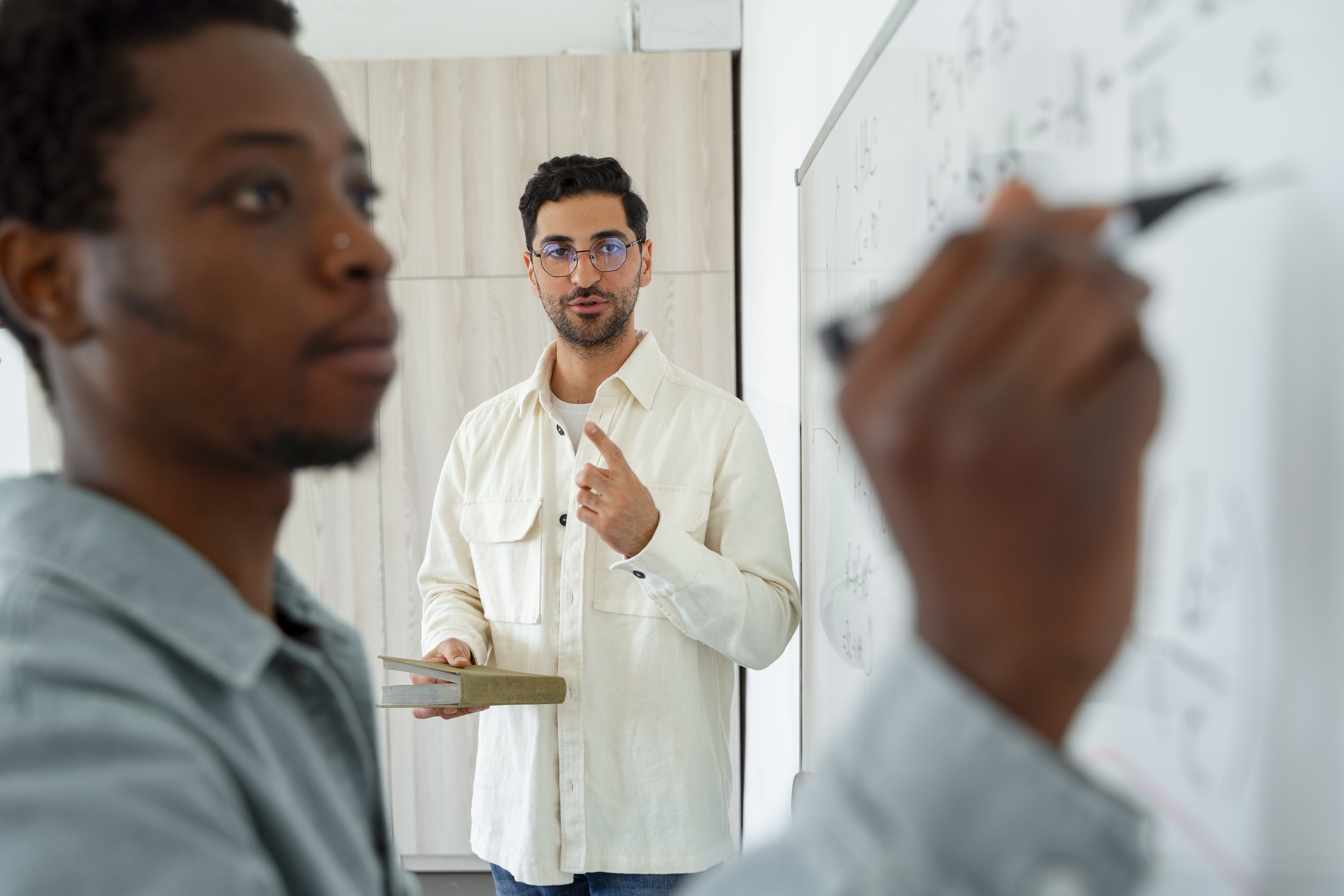Formateur écrit des équations au tableau devant un élève