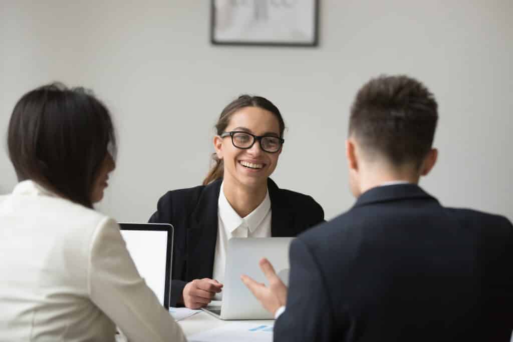 Femme souriante en entretien avec deux personnes autour d'une table