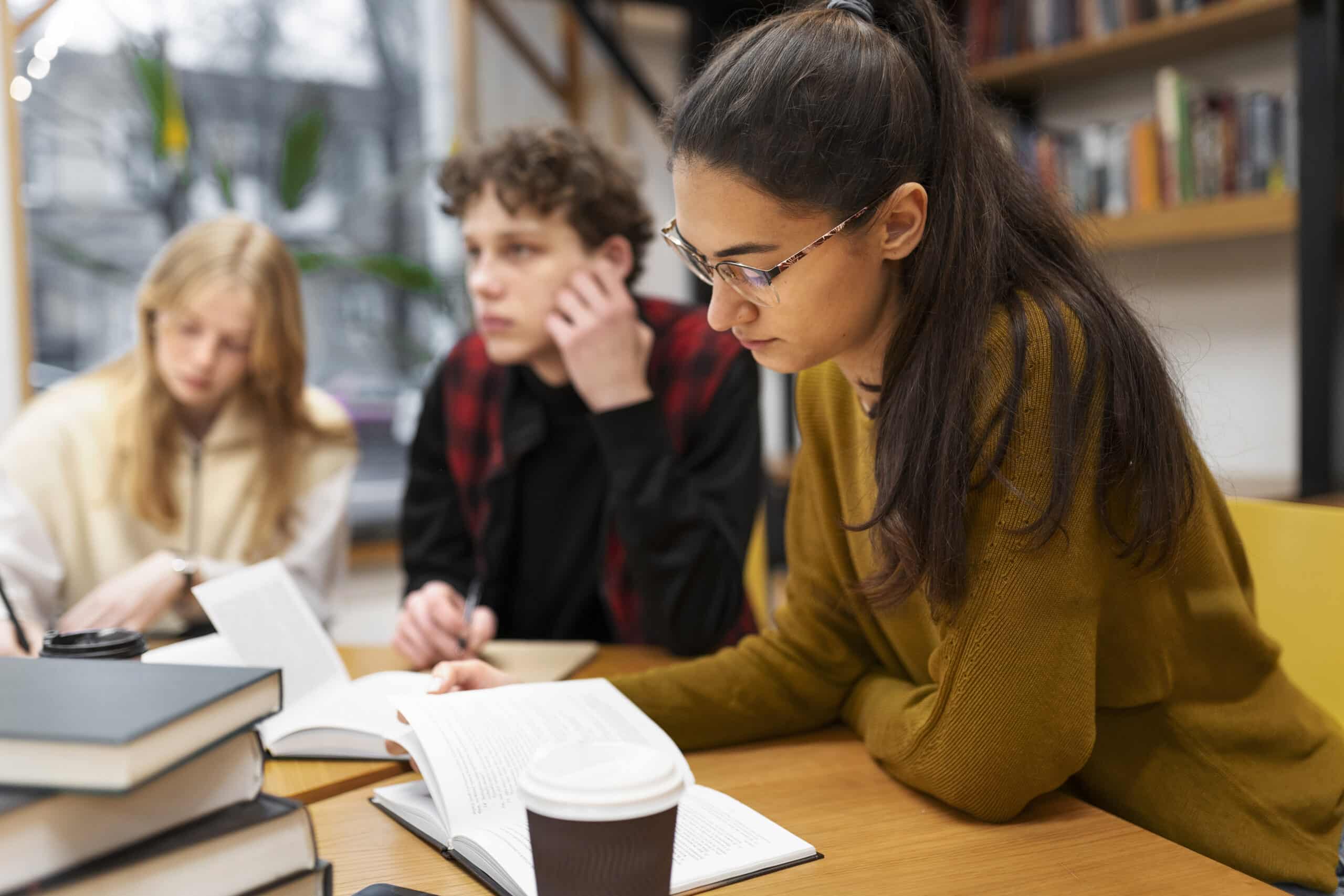 Étudiants en groupe de travail autour de livres, dans une bibliothèque