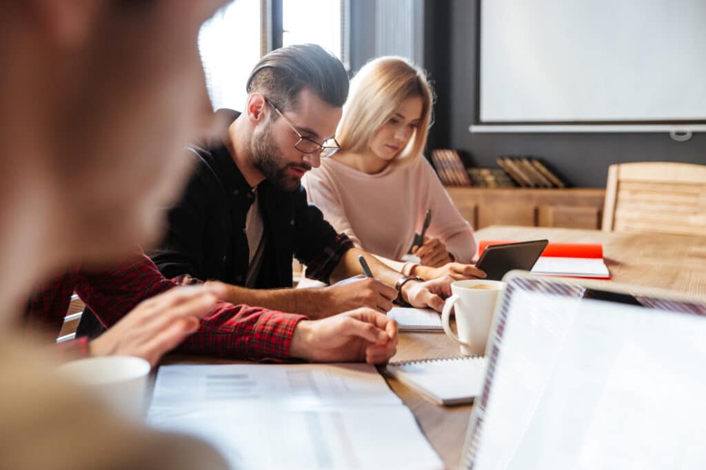 Collègues travaillent ensemble autour d'une table, ordinateurs ouverts