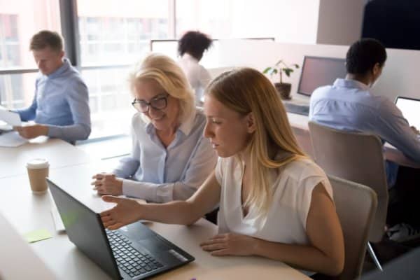 Commerciale présentant une offre à des clients autour d’un ordinateur