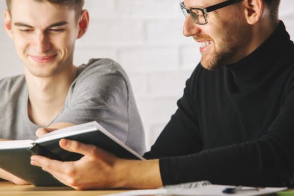 Deux jeunes adultes souriants remplissent des documents