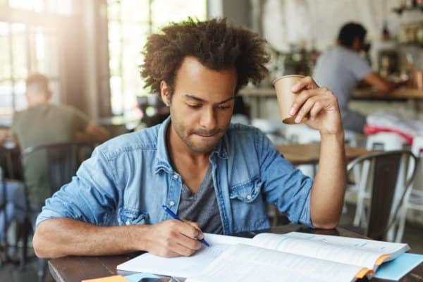 Homme concentré sur ses notes, un café à la main