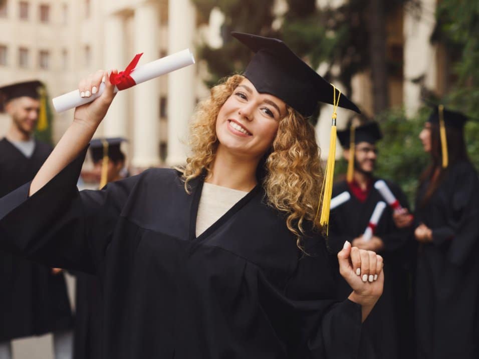 Jeune diplômée en toge, souriante, lors d’une remise de diplômes