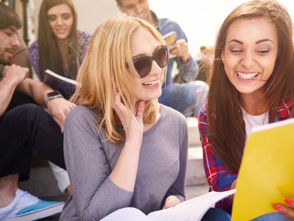 Deux étudiantes rient ensemble en travaillant sur leurs cours