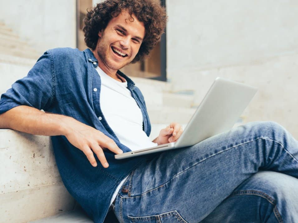 Un homme souriant travaille sur son ordinateur portable