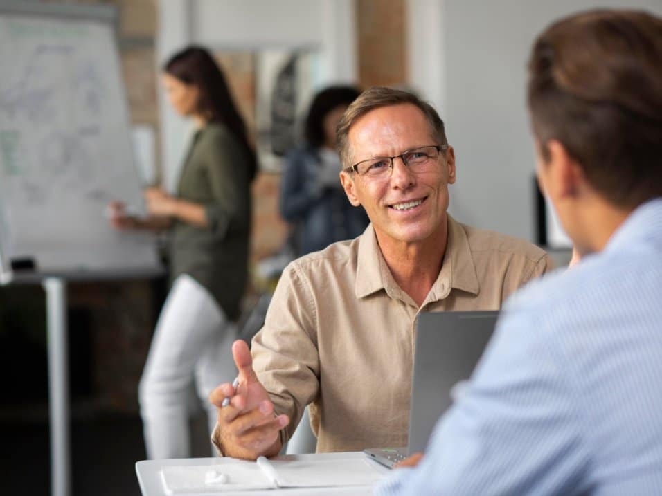 Un salarié souriant échange avec un collègue dans un bureau