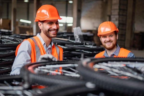 Deux techniciens portant casque et gilet de sécurité dans un atelier