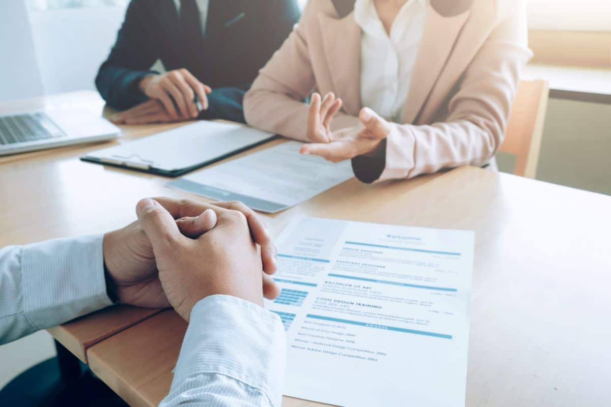 Entretien autour d'une table : deux personnes face à face, CV posé devant elles