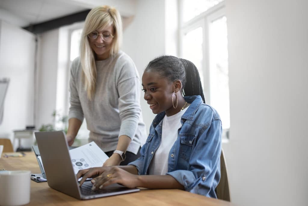 Une formatrice accompagne une collaboratrice devant un ordinateur portable