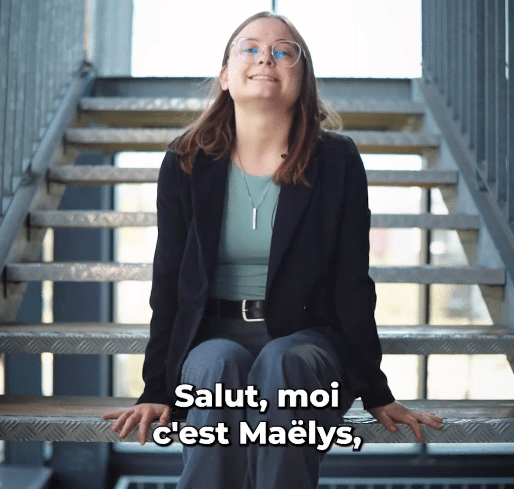 Maëlys, assise dans un escalier, se présente en vidéo